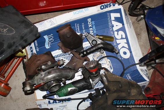 Turbocharger, exhaust manifold, and other engine parts are laid out on a Lasko box
