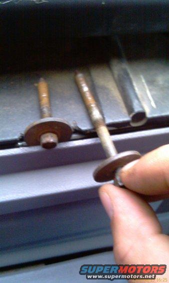 Two rusty bolts with washers, one held by a hand