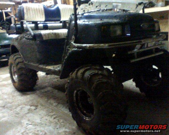 Mud-covered golf cart with oversized tires and a custom bumper