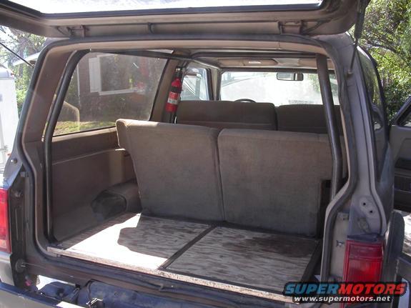 Interior cargo area of an SUV with folded-down rear seats and plywood flooring