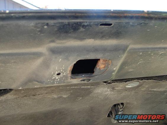 Underside of a car hood showing rust around a mounting hole. Supermotors.net logo visible