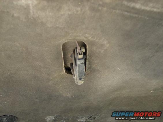 Underneath a 1992 Ford Taurus hood, a hood latch mechanism is visible in a cutout