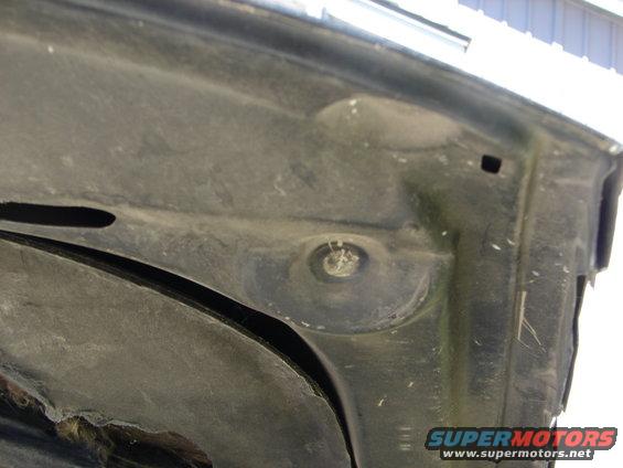 Underside of a dark-colored car hood with visible dust and a bolt