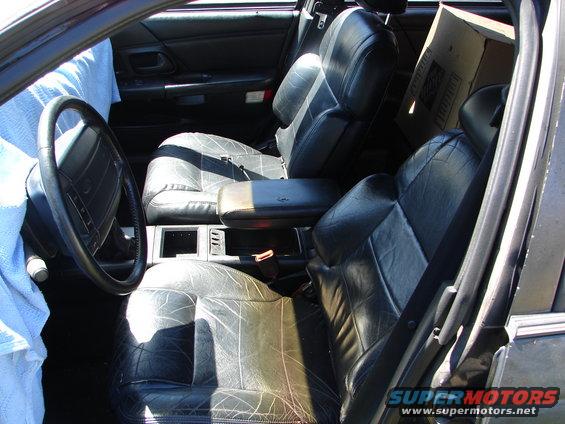 Interior view of a car with leather seats, steering wheel, and a box in the back seat