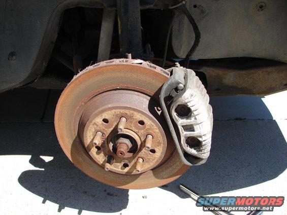 close-up of a rusty car brake rotor with a caliper
