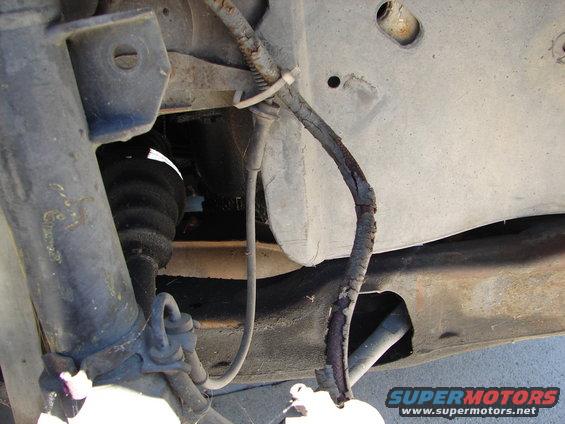 Vehicle undercarriage showing a cracked brake line and suspension components