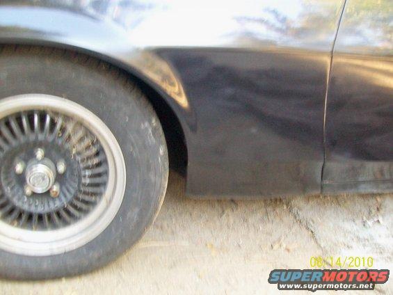 Close-up of a car's front fender and wheel, showing a seam and part of the door