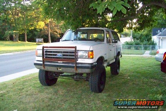 White Ford Bronco with a brush guard and lifted suspension parked on grass