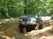 1995 Ford Bronco - A black 1995 Ford Bronco tackles a challenging off-road path, with another vehicle visible in the background.