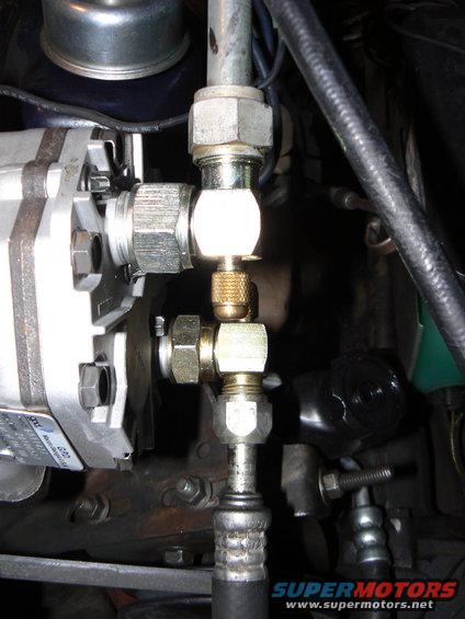 Close-up of an AC system's high-pressure service port and lines with brass fittings