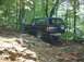 1995 Ford Bronco - 1995 Ford Bronco navigates a challenging, rocky off-road path through a forest.