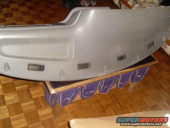 Gray dashboard section with air vents, resting on a wooden stand with purple fabric