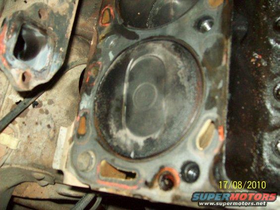 Engine cylinder head with carbon buildup and visible piston top, close-up