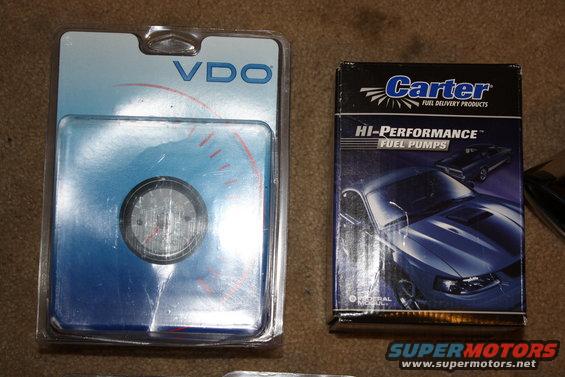 VDO gauge in packaging next to a Carter Hi-Performance Fuel Pumps box showing a blue Mustang