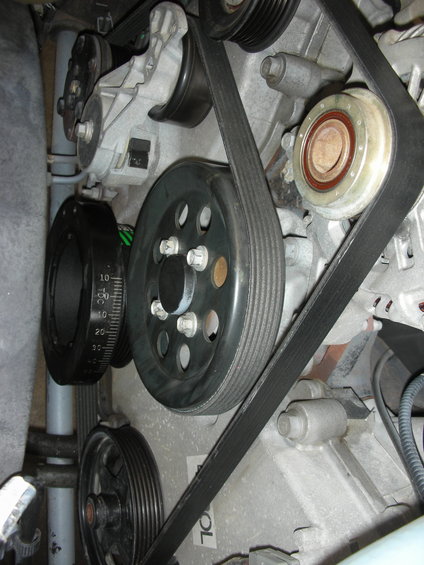 Close-up of engine belts and pulleys, including a harmonic balancer with degree markings