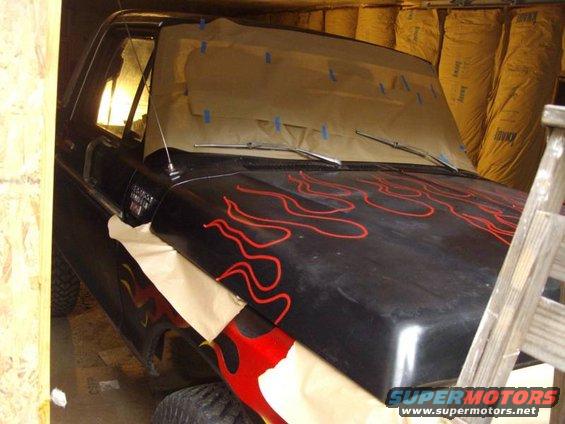 Black 1978 Ford Bronco with red flame decals on hood and fender, partially covered with masking paper