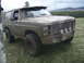 1985 Ford Bronco - This heavily muddied SUV, likely from the early 1980s, is shown in a rural outdoor setting.