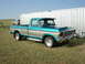 1979 Ford F-150 - A teal and tan 1979 Ford F-150 pickup truck is parked in front of a corrugated metal wall, with another vehicle visible in the background.