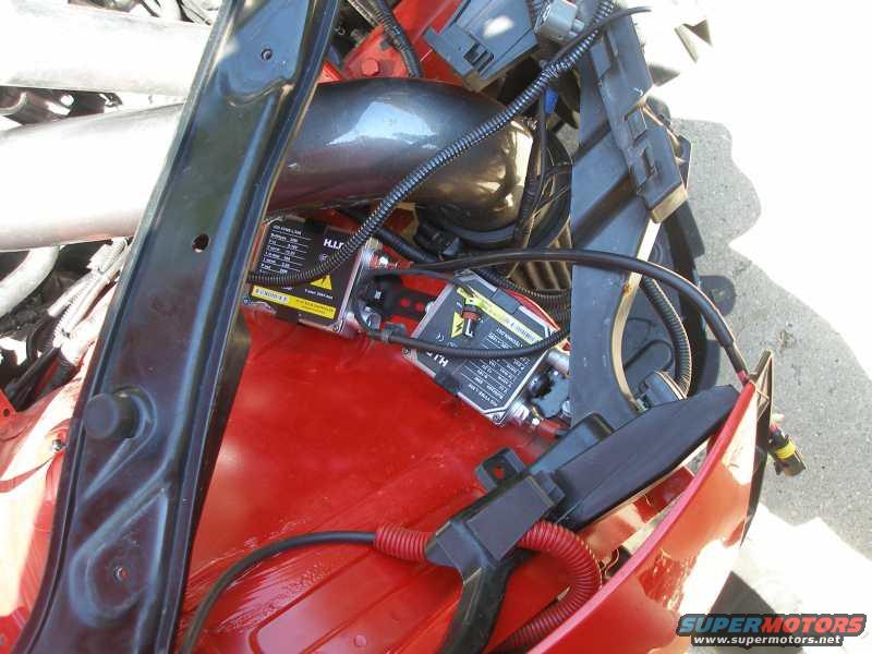 Close-up of a car's engine bay showing a ballast and wiring for a headlight