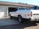 1973 Ford Ranchero - A white coupe utility with a dark roof is parked in a driveway next to an open garage door.