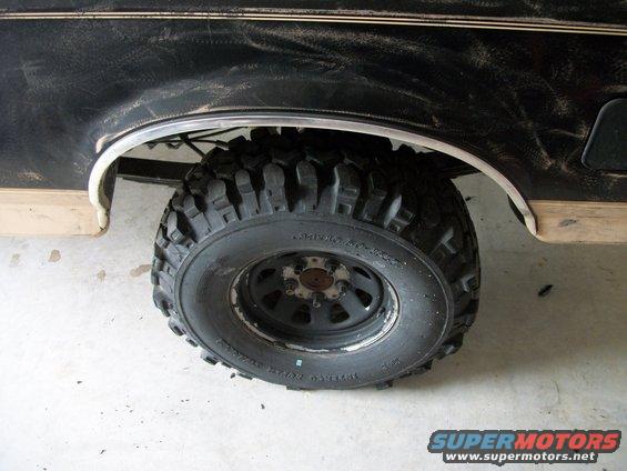 1990 Ford Bronco rear wheel with off-road tire, side view of fender and trim