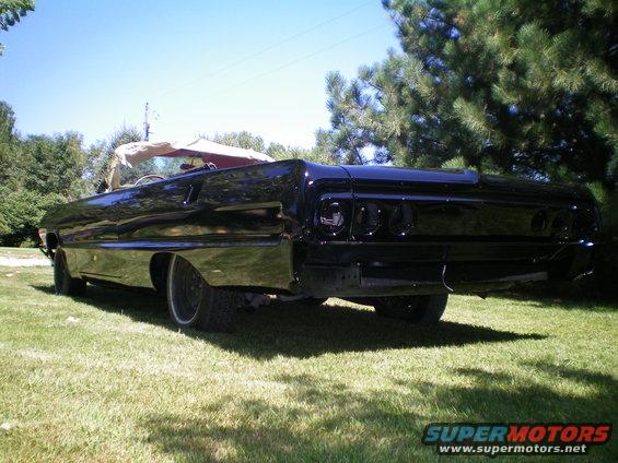 Black 1964 Chevrolet Impala convertible parked on grass, rear view