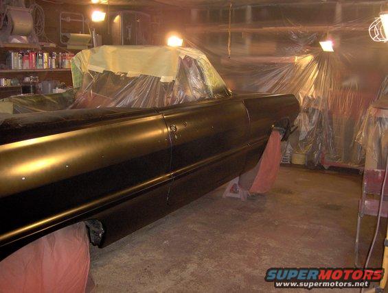 1964 Chevrolet Impala side view, covered in plastic for painting in a garage
