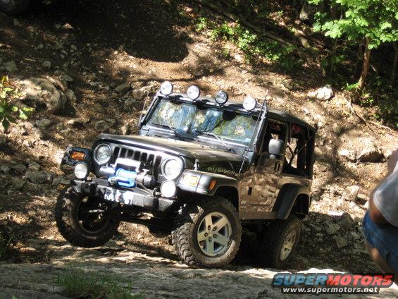 Black Jeep Wrangler Rubicon with winch and light bar on rocky terrain