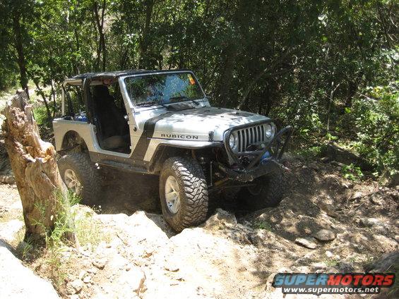 Silver Jeep Wrangler Rubicon off-roading on a rocky trail