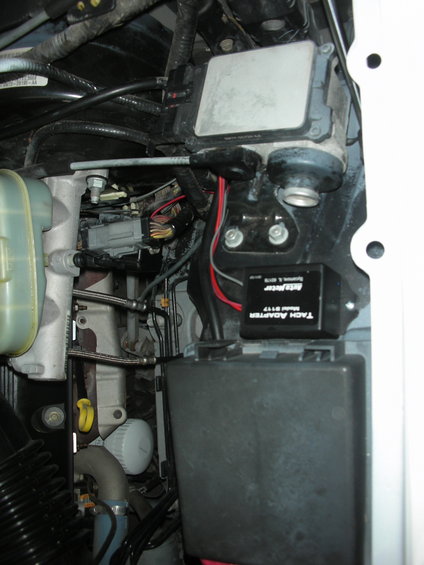 Engine bay with Autometer tach adapter, fuse box, and fluid reservoir