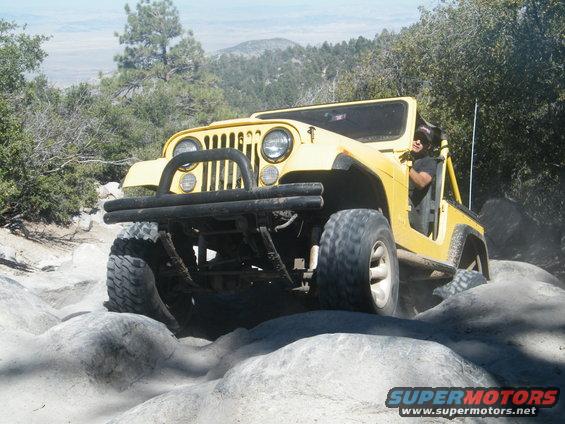 Yellow Jeep Wrangler navigating rocky terrain