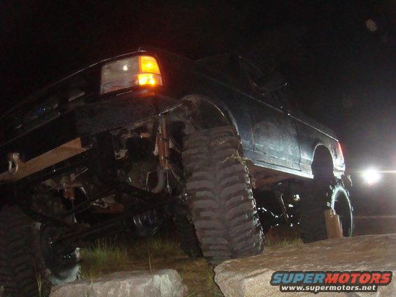 1992 Ford Bronco 3q-front view, black, with large tires on rocks at night