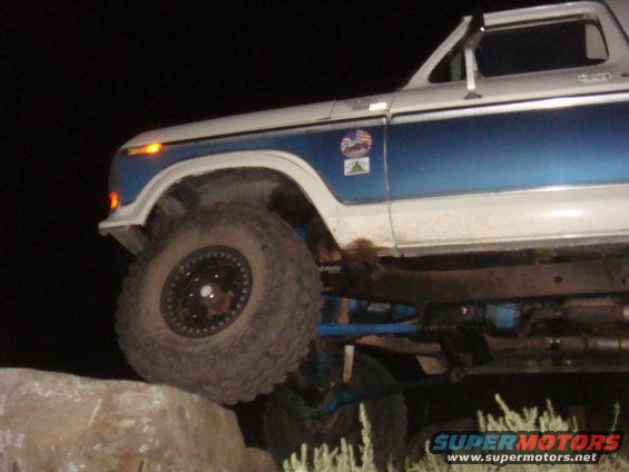 White and blue Ford Bronco with off-road tires on rocks