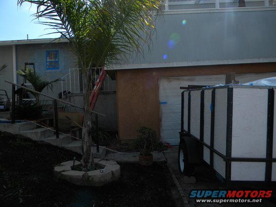 Trailer parked next to a garage with a palm tree in the foreground