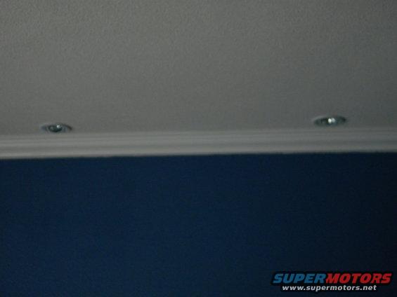 Two recessed ceiling lights above a blue wall and white molding