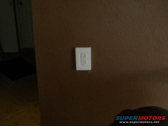 White light switch on a brown wall