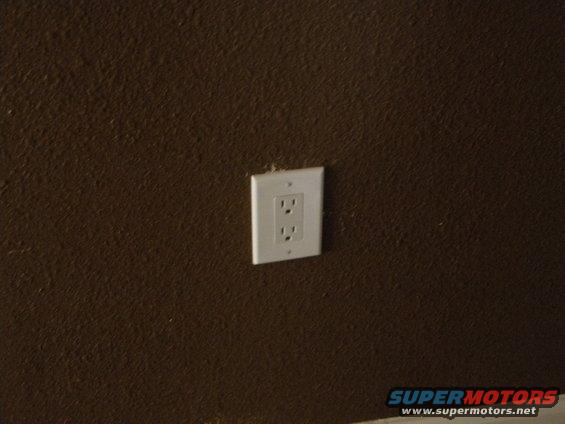 Electrical outlet on a textured brown wall