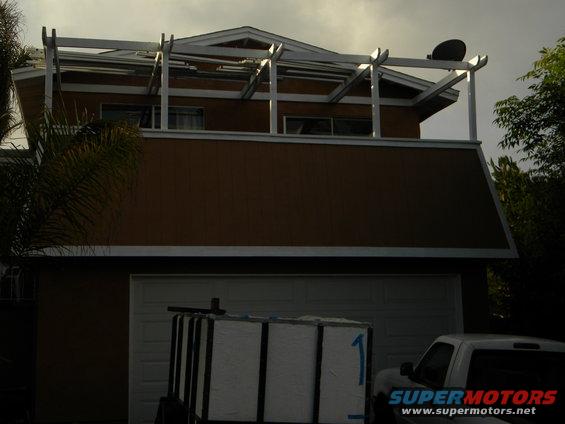 House with a garage, a trailer with white boxes, and a white truck parked to the right