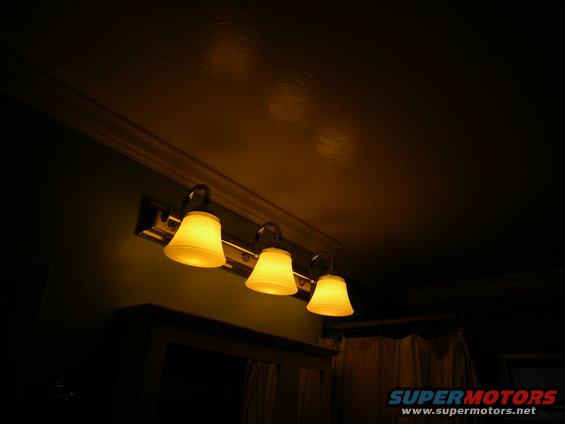 Three yellow glass vanity lights above a mirror