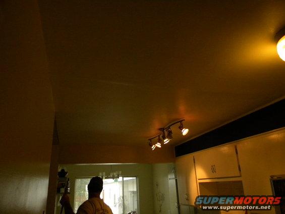 Interior view of a room showing a ceiling with track lighting, cabinets, and a window