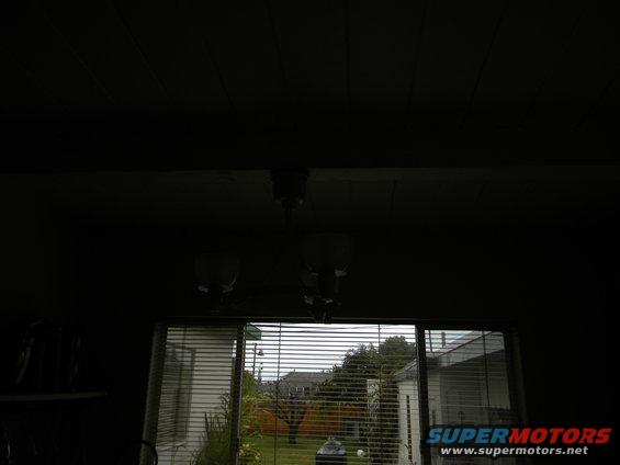 Interior of a dark room looking out a sliding glass door to a backyard