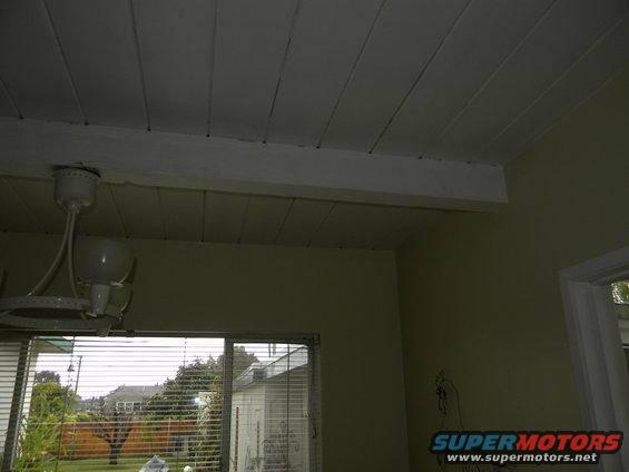 Interior ceiling with a fan and a window showing houses and trees outside