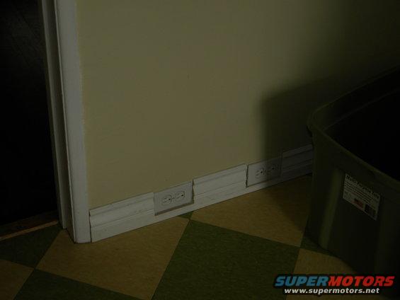 Wall with electrical outlets and a green storage bin