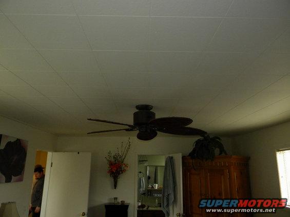 Room interior with ceiling fan, doorway, and furniture. Watermark says SUPERMOTORS
