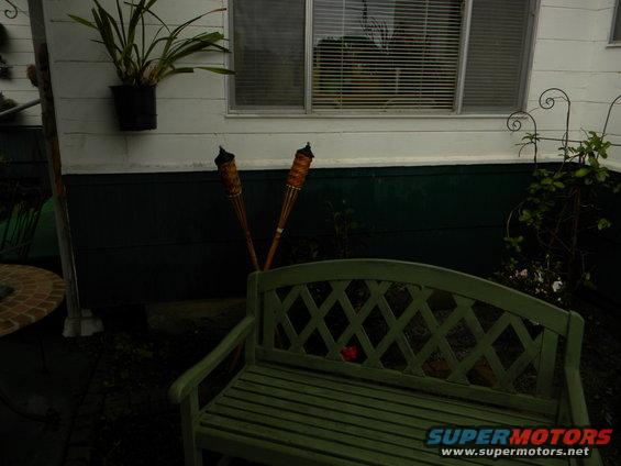 Patio scene with green bench and tiki torches