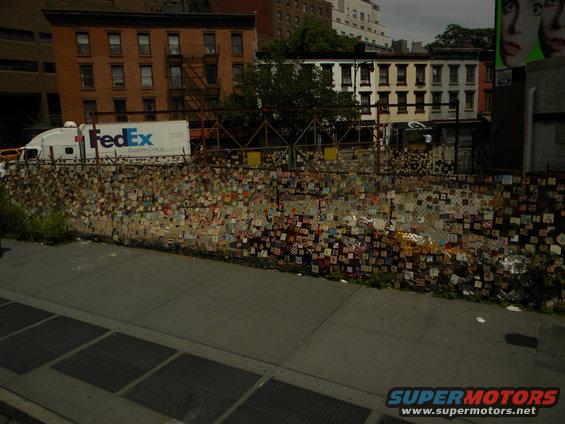 FedEx truck parked behind a chain-link fence covered in many small, colorful squares