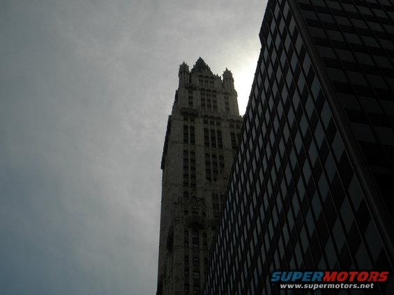 Two skyscrapers against a cloudy sky, one with ornate gothic architecture, the other modern glass