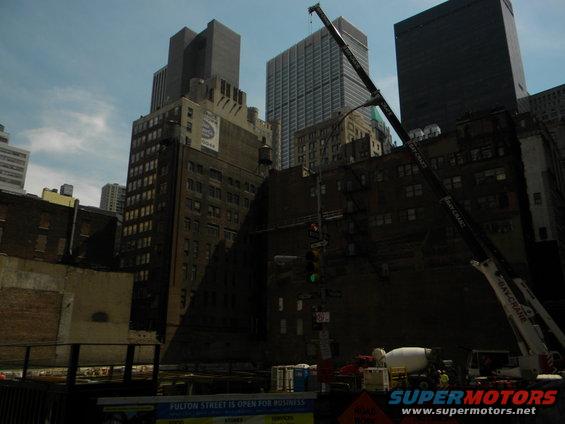 construction site with crane and cement mixer, tall buildings in background