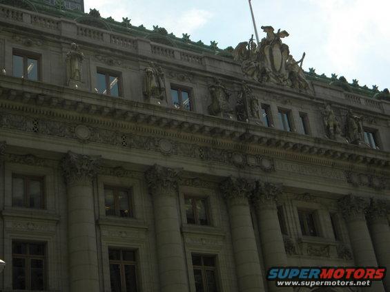 Ornate building facade with statues and columns under a cloudy sky