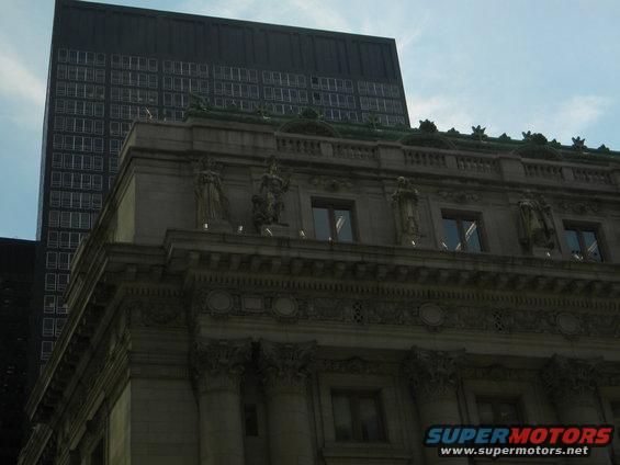 Ornate building facade with statues and a modern skyscraper behind